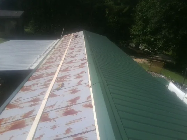 Old rusted panels beside newly installed green metal roofing — Wind Damage Roof Repair by Roofing Brothers in Pickens