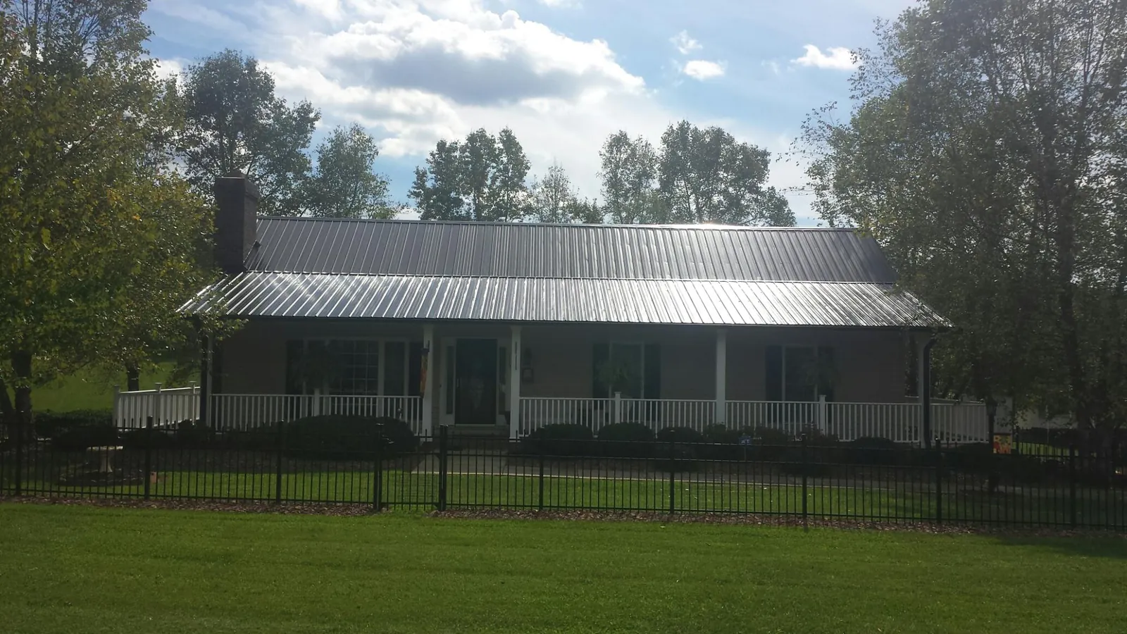 Gray metal roof on a brick ranch with a full width front porch — Gutter Guard Installation work by our crew in Pickens