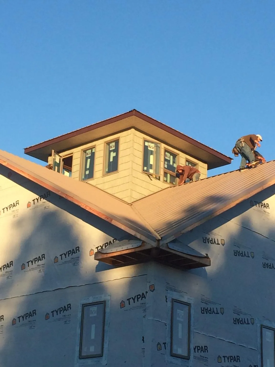 Roofers working around a rooftop cupola on a new metal roof at sunset — Roof Waterproofing in Pickens by Roofing Brothers